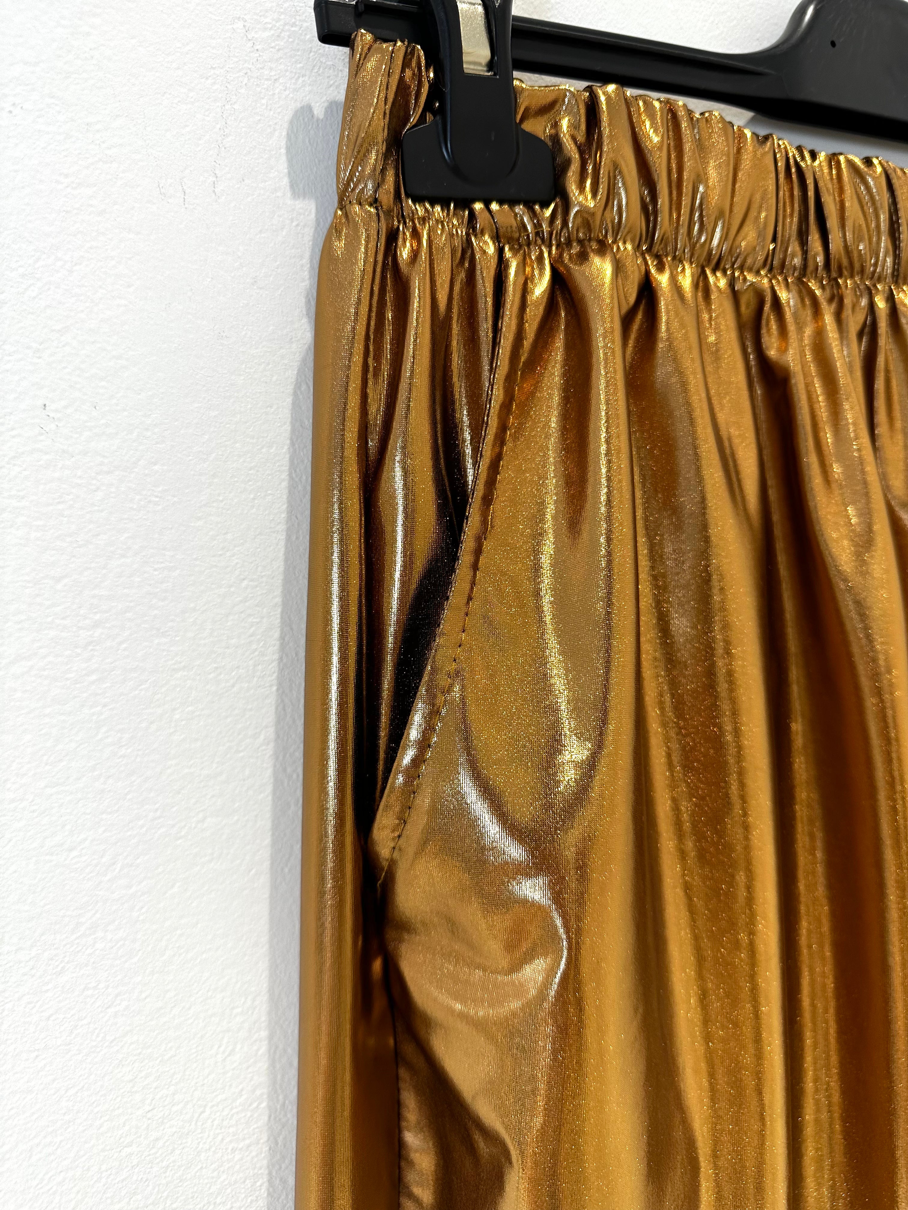 Calças metalizadas maleáveis com elástico à cintura apresentados by Tanzanna dourado metalizado pormenor.