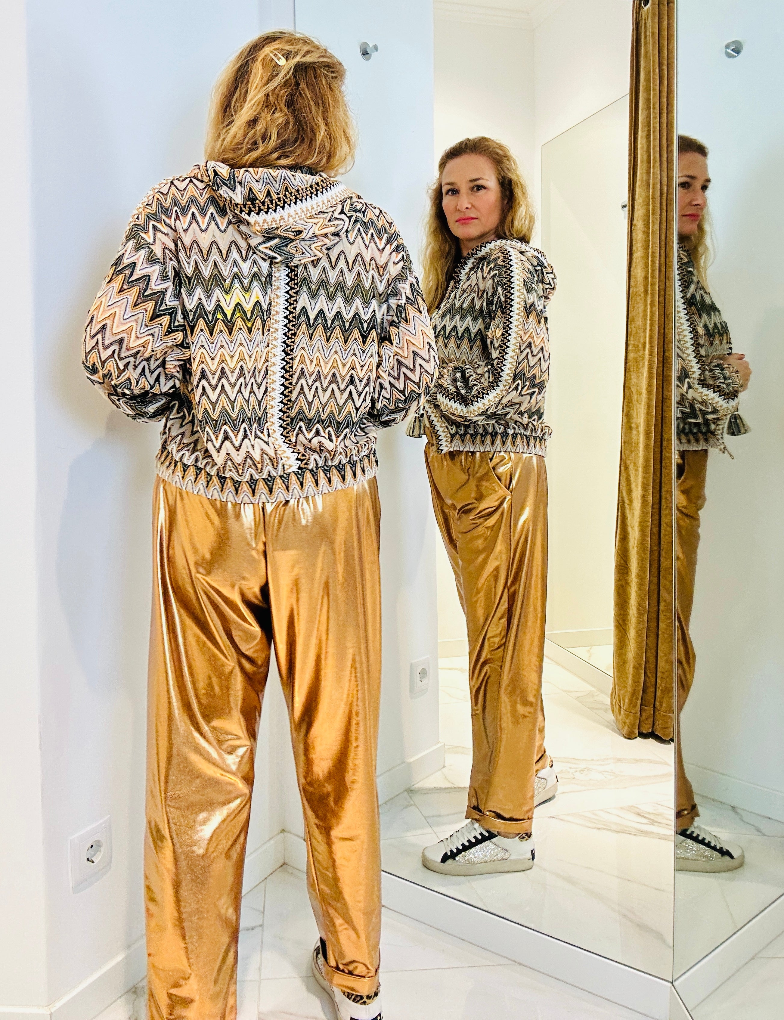 Calças metalizadas maleáveis com elástico à cintura apresentados by Tanzanna dorado metalizado atrás.